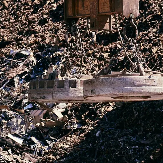 Magnetic crane sorting scrap metal in an industrial yard